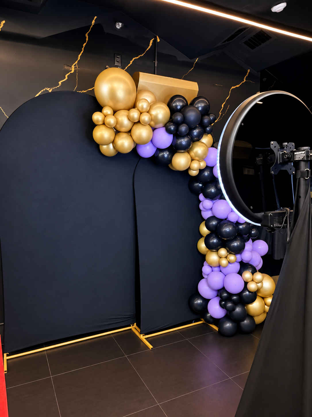 Black, gold and purple balloon garland with photo booth backdrop by SobyCam Event Services